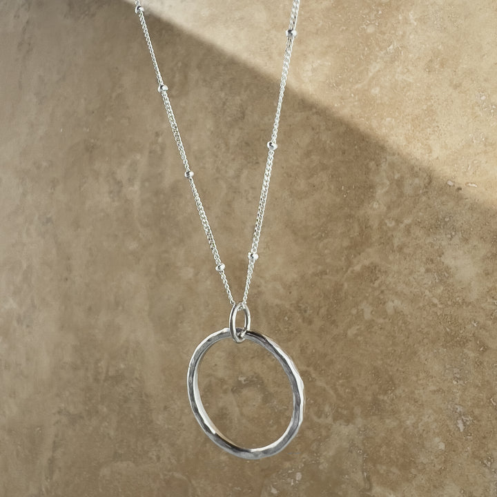 Circle Necklace. Made of sterling silver, this open-circle pendant features a stunning hand-hammered texture that reflects light.