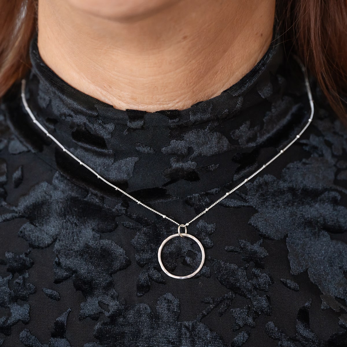 Celebrate timeless beauty and connection with the Aurora Unity Circle Necklace. Made of sterling silver, this open-circle pendant features a stunning hand-hammered texture that reflects light. Worn on black top.