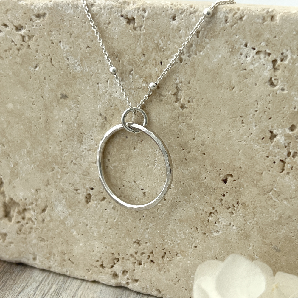 Circle Necklace. Made of sterling silver, this open-circle pendant features a stunning hand-hammered texture that reflects light. 