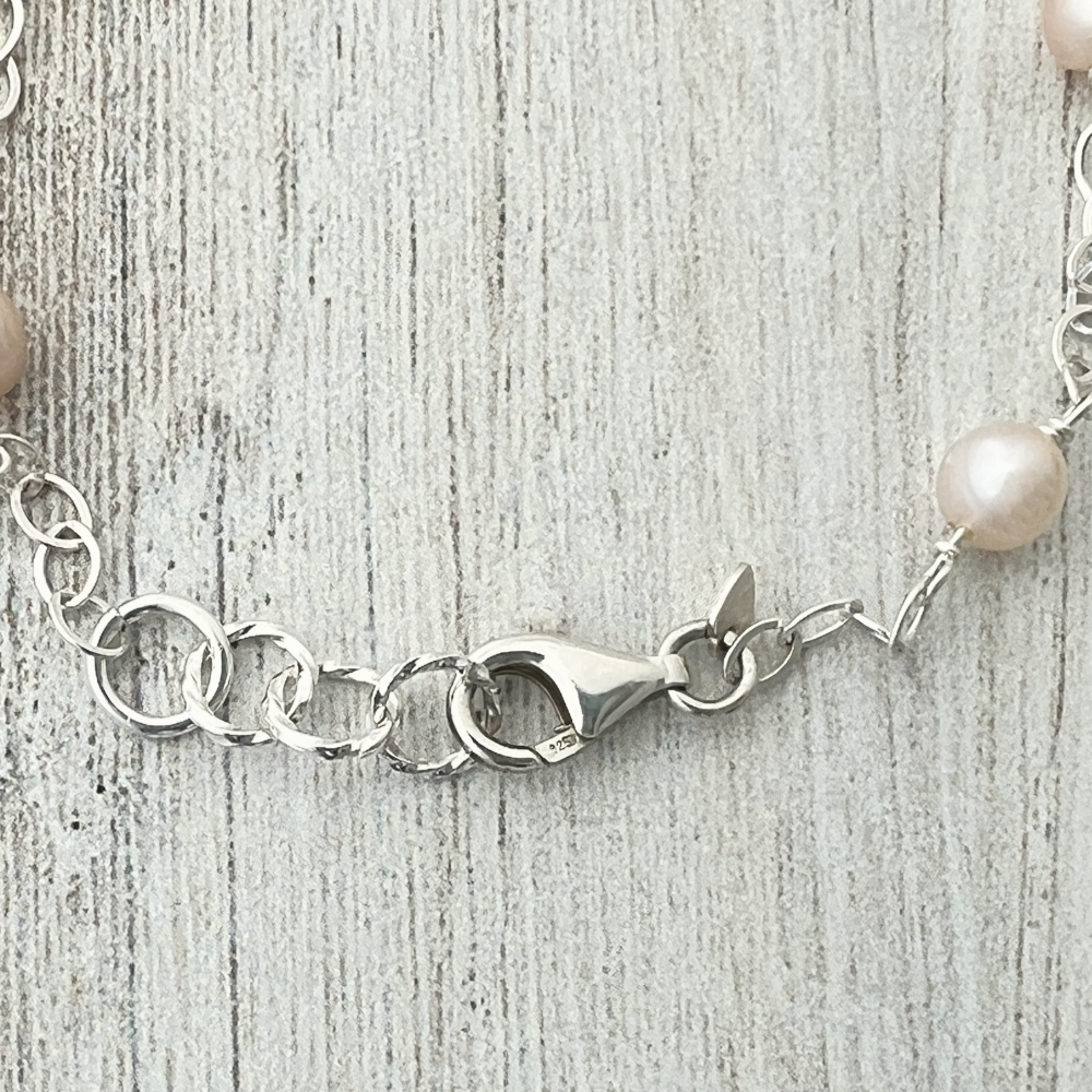 Freshwater pearl and sterling silver bracelet showing the lobster clasp detail on a textured gray background