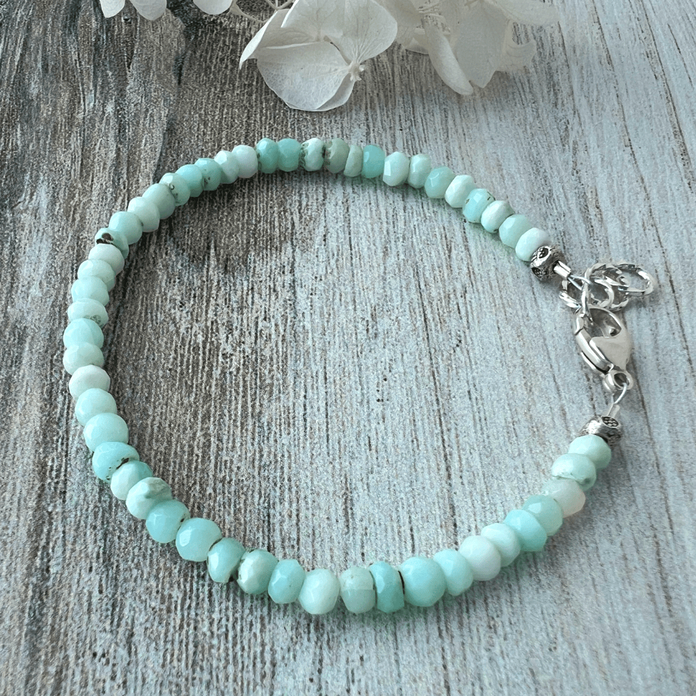 Peruvian Blue Opal beaded bracelet with a sterling silver lobster clasp on a wooden surface