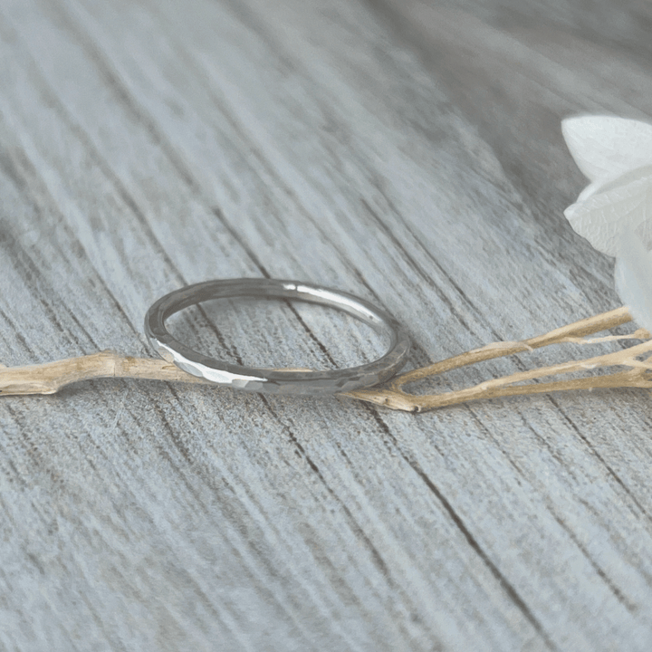 Thin Sterling Silver stacking ring on a wooden surface with a white flower