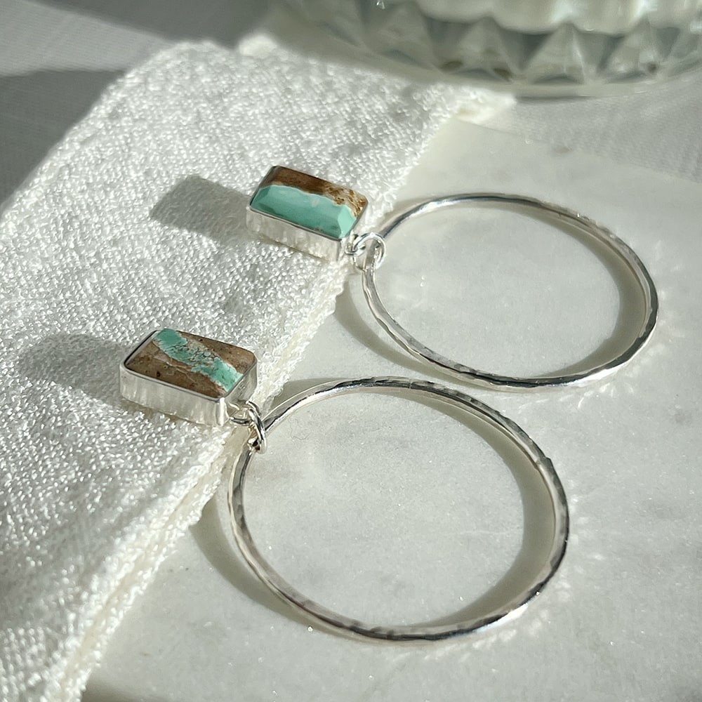 Turn heads with these one-of-a-kind Turquoise stud hoops, crafted with sterling silver and adorned with natural Royston Turquoise - mined in Nevada. The hammered texture of the hoops adds a touch of shimmer, while the stunning matrix of the turquoise exudes a southwestern charm. Handcrafted in California.