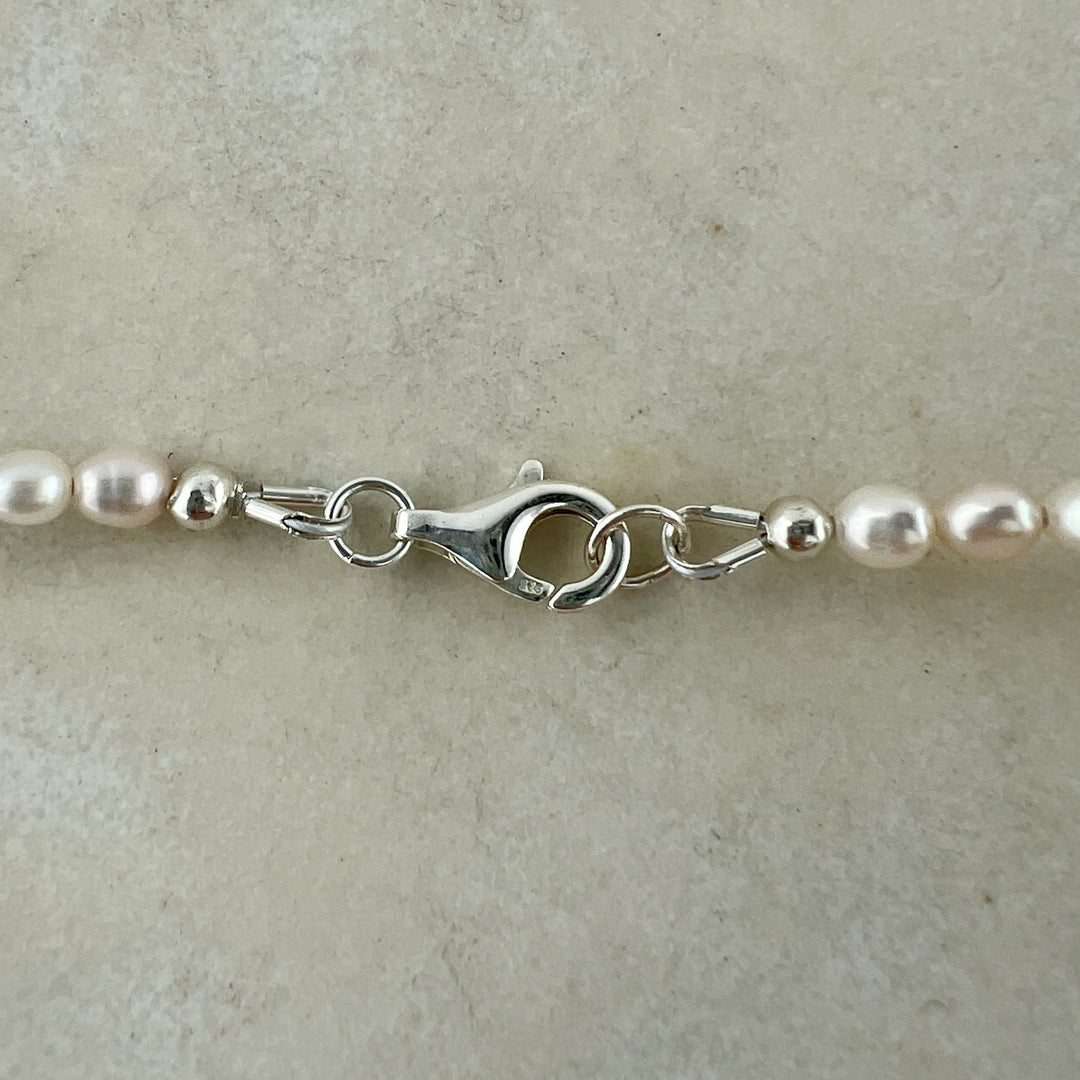 Pearl necklace with silver clasp on a beige background